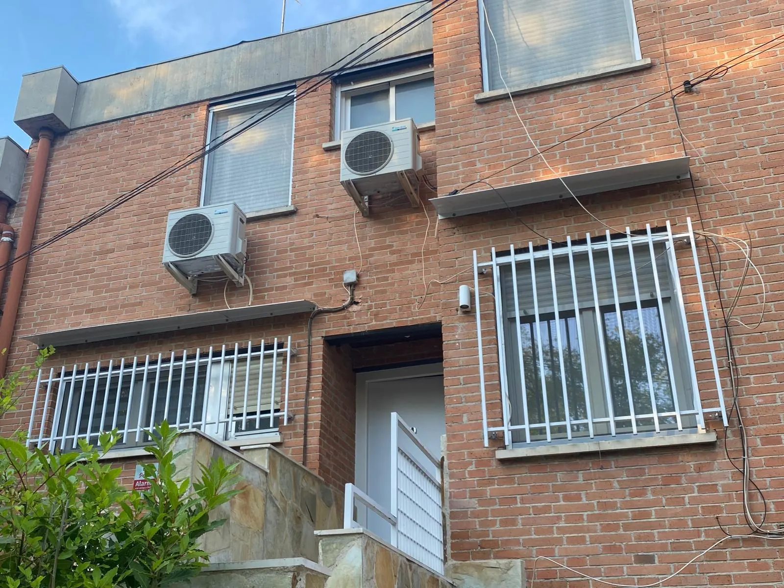 Fachada de ladrillo con cableado de telecomunicaciones visible, antes del saneamiento